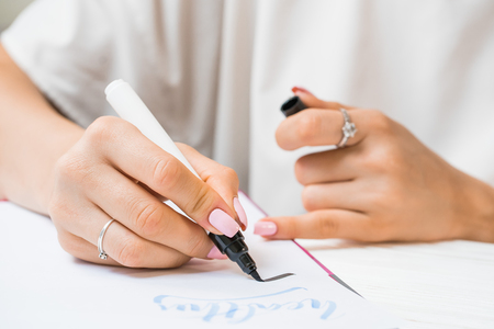 Calligrapher student practices in writing word inspire with green marker on canvas. Creative artist freelancer working on project at home studio. Lettering, handwriting concept.の写真素材