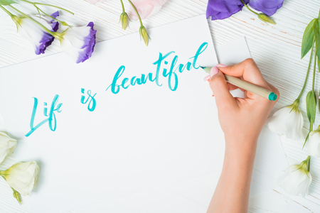Life is beautiful text. Font of lettering word on white paper with green ink by calligrapher. Flowers frame. Graphic design, lettering, concept.の写真素材