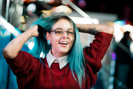 Hipster girl waving head in different directions, playing with dyed blue hair. Woman with nose...