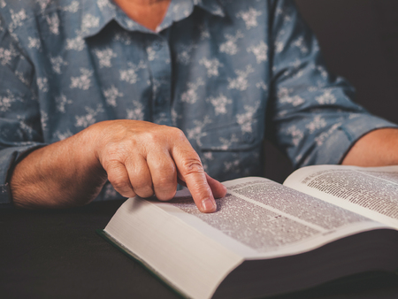 Old woman reading thick book at home. Grandmother with Bible. Concentrated elderly pensioner with...