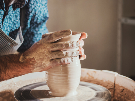 Traditional pottery making, man teacher shows the basics of pottery in art studio. Artist operates...