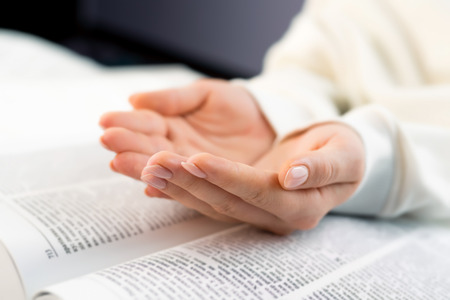 Unrecognizable woman reading big book - Holy Bible and praying. Christian studying scripture. Student in the college library preparing for exams. Learning, gratitude, religion conceptの写真素材