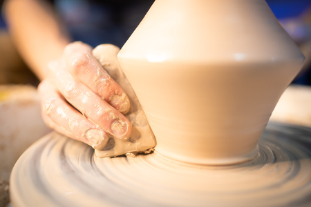 Working process of mans work at potters wheel in art studio. Unknown craftsman creates jug. Focus on hands only. Small business, talent, invention, inspiration conceptの写真素材