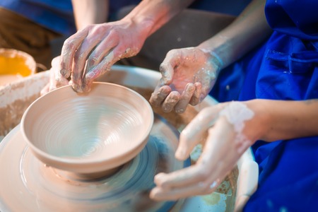 Traditional pottery making, man teacher shows the basics of pottery in art studio. Artist operates hands, which gently creating correctly shaped jug handmade from clayの写真素材
