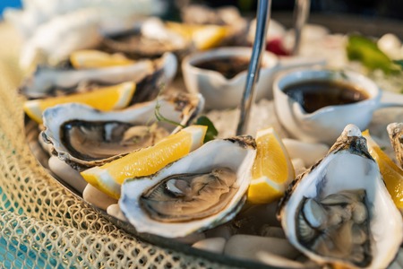 Fresh oysters with lemon on white plate in restaurant