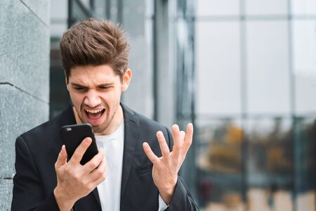 Businessman screaming on mobile phone. Having nervous breakdown at work, screaming in anger, stress management, mental distress problems, losing temper, reaction on failureの写真素材
