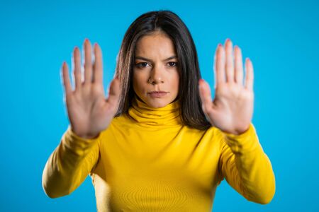 Woman disapproving with NO hand sign gesture. Denying, rejecting, disagree, portrait of beautiful student girl or businesswoman on blue background.の写真素材