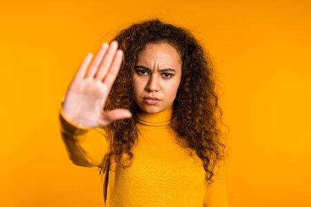 pretty curly woman disliking and rejecting gesture by stop palm sign. Portrait of young successful...