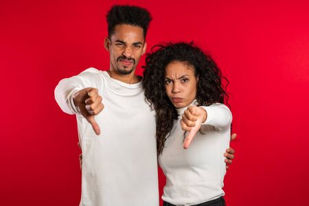 Young african couple showing thumb down gesture at camera.の写真素材