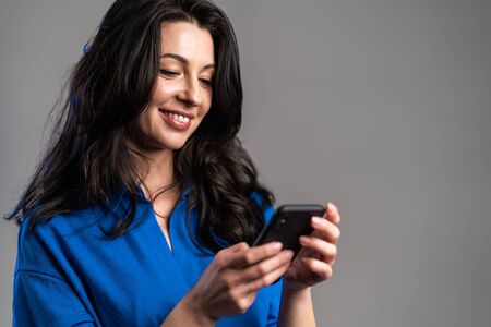 Mature woman sms texting, using app on smartphone. Pretty adult lady surfing internet with mobile...