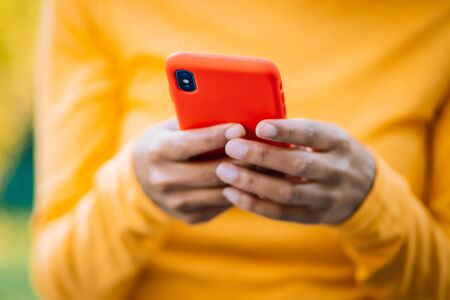 African woman using mobile phone over green background. Close up beautiful hands holding smartphone. Black female using technologyの写真素材