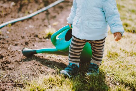 Little toddler baby boy walking with big watering can in garden. Adorable child helping parents to grow vegetables. Activities outdoors, love, family concept.の写真素材