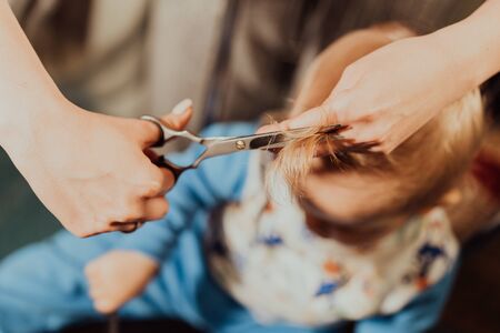 First haircut of little baby boy at home by parents. Black and white portrait.の写真素材