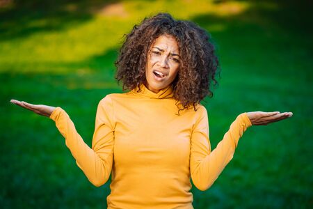 Unsure african american woman shrugs her arms, makes gesture of I dont know, care, cant help...