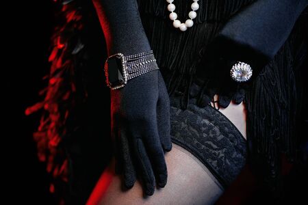 Old-fashioned woman dressed in style of Great Gatsby era shows her legs and adjusts nylon mesh...