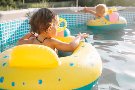 Happy babies boys bathing in inflatable ring. Swimming pool at summerの写真素材