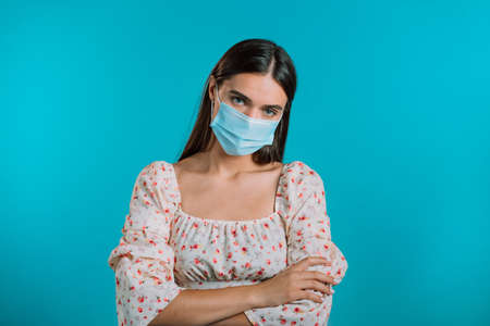 Angry annoyed woman in medical mask keeping arms crossed and staring at camera with sceptical and distrustful look, feeling mad at someone. Human facial expressions, emotions and feelings.の写真素材
