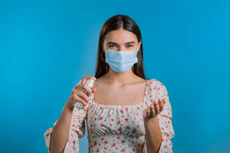 Woman in protective mask applies disinfectant antiseptic to her hands. Stop virus concept, bacteria protection.の写真素材