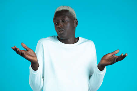 Young african unsure man shrugs his arms, makes gesture of I dont know, cant help anything.の写真素材