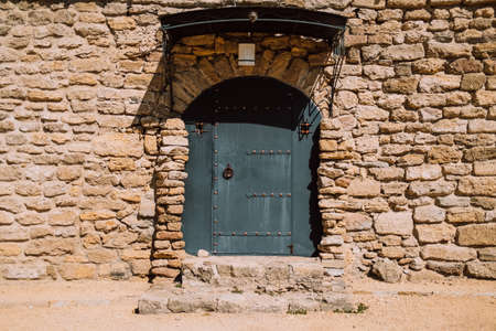 Ancient stonewall with black door. Antique building exterior of fortesの写真素材