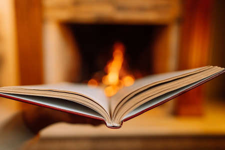 Stunning view of open book against burning fire from fireplace background. Paper literature, education concept.の写真素材