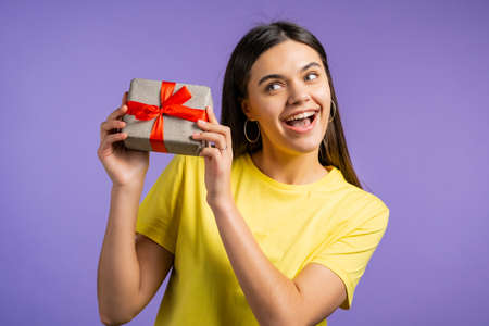 Beautiful woman received gift box with bow. She is happy and flattered by attention. Girl smiling...