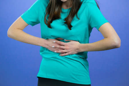 Woman squeezing belly with hands because of abdominal pain. Lady suffering from stomach ache....