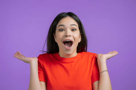 Young woman is very glad, she screaming wow loud. Concept of sales, profitable offer. Excited happy lady on violet studio background.の写真素材