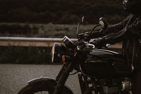 Portrait of confident motorcyclist woman in motorcycle helmet. Young driver biker looking away outdoors alone on highway. Ready for trip. Cafe racers, motorbike aesthetics and vintage design concept.の写真素材