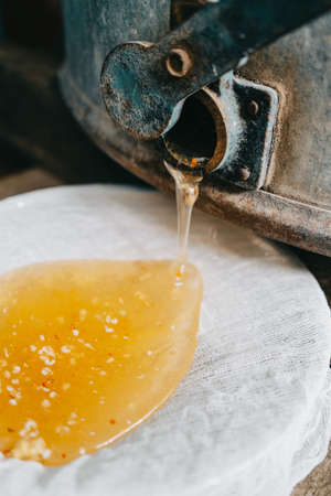 Pumping honey with an old retro extractor centrifuge. Production of nectar in apiary. Manual labor, insect care. Beekeeping culture concept, yellow harvest. High quality photoの写真素材