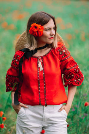Young pretty woman in poppies red field. Nature, flowers background. Lady in Ukrainian embroidered shirt. National traditional clothing. Culture concept.の写真素材