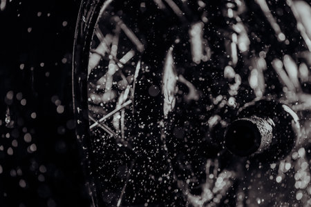 Washing with water rear wheel, exhaust pipe and chain of classic black motorbike under blue neon light. Dirty motorcycle at wash after off-road driving. Caferacers style Maintenance of motor vehiclesの写真素材