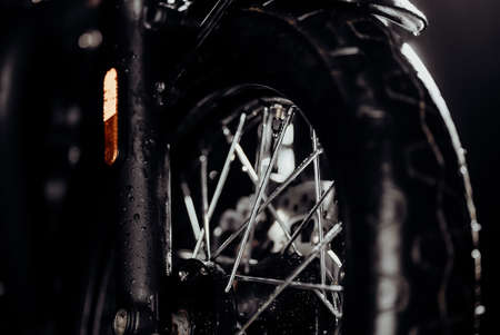 Motorcycle at wash after off-road driving. Washing front wheel with disc brakes with water. Classic black motorbike. Caferacers style. Maintenance of motor vehiclesの写真素材