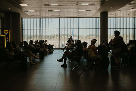 Corfu, Kerkyra, Greece - September 2021. People, passengers sitting in chairs at airport lounge and waiting for their flight.のeditorial素材
