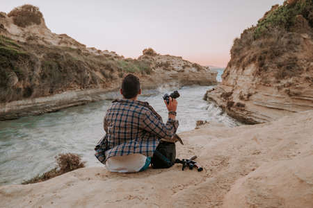 Stranger man hipster photographer sitting on seashore near love channel - Canal DAmour on Corfu island. Nature, sea videography.の写真素材