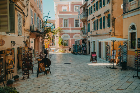 Corfu, Greece - September 2021. Beautiful cozy narrow street in old greek town. Historic european centre with souvenir shops for tourists. Cityscape concept.のeditorial素材