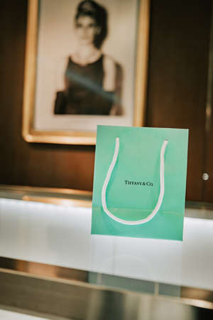 Barcelona, Spain - December 2021. Tiffany and Co branded paper bag from world-famous American fashion brand on counter. Luxury, trendy jewelry gift.のeditorial素材