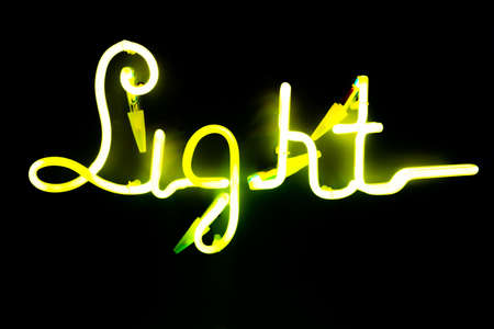 Illuminated letters written light on dark black background. Neon yellow words. Abstract picture.の写真素材