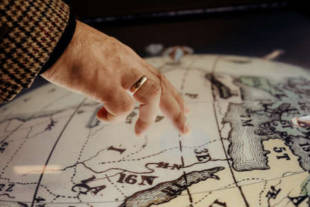Male hand tapping on globe. Our planet, world map, geography education concept. Modern technology.の写真素材