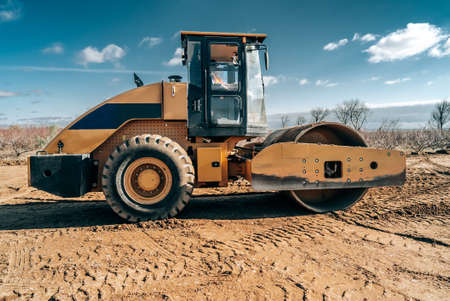 View of new dirt soil road construction with vibrating roller machine. Road surface repair. Heavy...