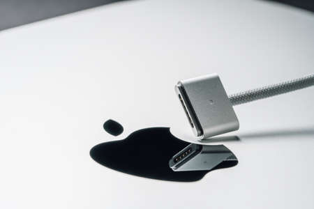 Barcelona, Spain - January 2022. MagSafe 3 power adapter for new laptop. Macro view of charger for MacBook on Apple logo. Metal silver backgroundのeditorial素材