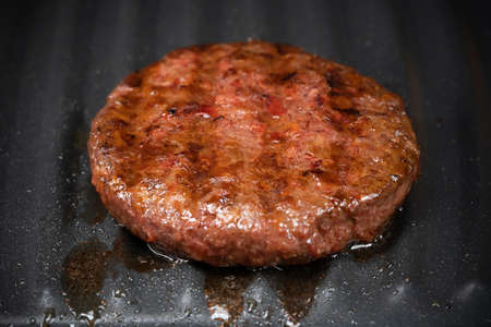 Process of roasting veggie plant-based meat cutlet on barbecue grill plate. Soybean fake patty, gluten free, non-meat vegetarian and vegan food concept. Raw for burger. Close-up photo.の写真素材
