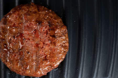Process of roasting meat steak on barbecue grill plate. Cooking beef or pork patty. Raw cutlet for burger. Close-up photo.の写真素材