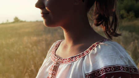 Ukrainian woman in vyshyvanka shirt with traditional ornament standing in wheat field. National costume - embroidery, texture, design, folk, handmade craft needleworkの写真素材