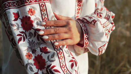 Ukrainian woman demonstrating beautiful details of embroidery ornament on vyshyvanka shirt. National costume - embroidered shirt, texture, design, folk, handmade craft needleworkの写真素材