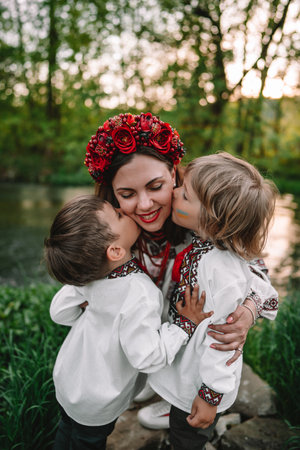 Little ukrainian boys kissing mother on cheeks. Happy family in traditional embroidery vyshyvanka shirts. Ukraine, brothers, sons, freedom, national costume.の写真素材
