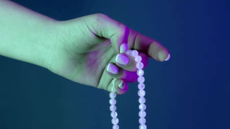 Woman praying and holding mala beads in hand for counts during mantra meditations. Lady on blue background. Spirituality, religion, God concept.の写真素材