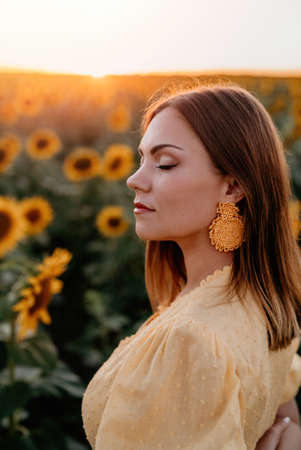 Pretty woman in retro dress posing in sunflowers field. Yellow colors, warm toning. Vintage timeless...