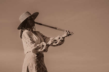 Woman plays on wooden flute - ukrainian telenka, tylynka. Retro toning. sepia. Folk music, sopilka concept. Musical instrument. Musician in traditional embroidered shirt - Vyshyvanka.の写真素材