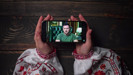 August 2022 - Kyiv, Ukraine. Watching online speech of President Volodymyr Zelenskiy on smartphone...